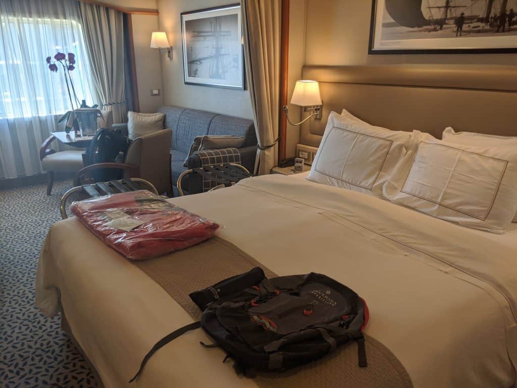 My Silversea Cruises cabin on the Silver Cloud—with Antarctic expedition gear laid out on the bed and a bottle of bubbly on the table