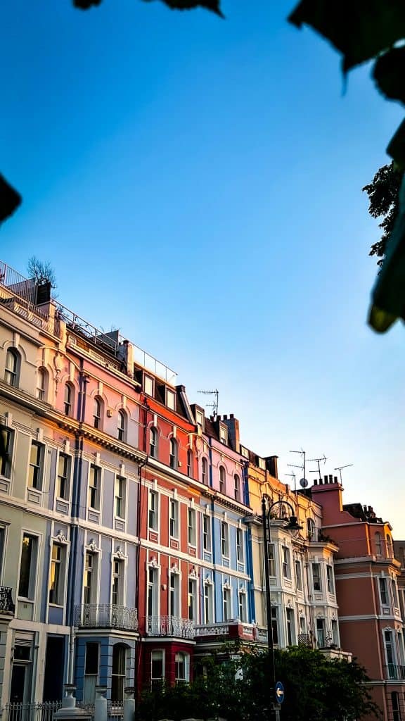 A row of colorful houses in London's Notting Hill neighborhood beneath a bright blue sky