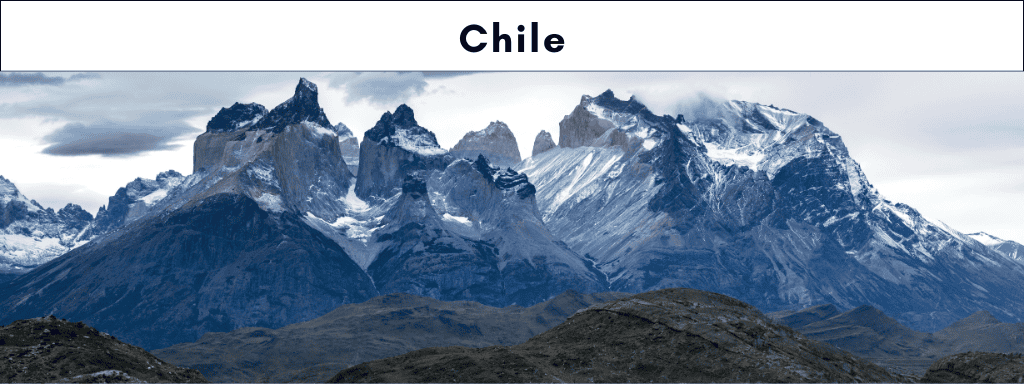 The silver snow-capped Torres del Paine massif mountains tower above green foot hills in Chilean Patagonia
